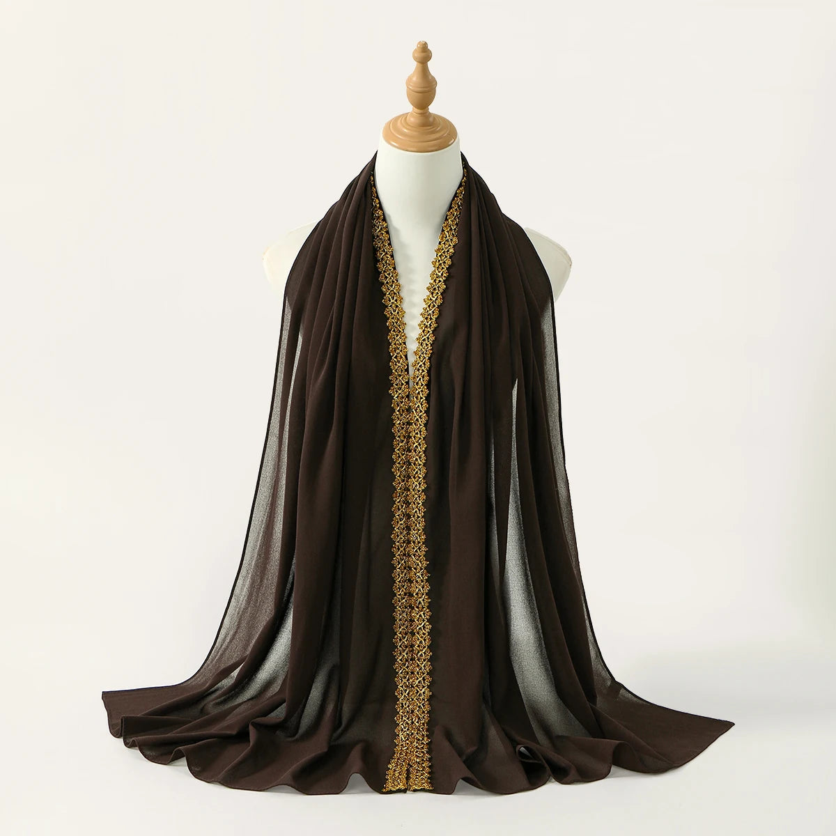 Pañuelo/chal de gasa marrón oscuro con detalle de strass dorados exhibido en el cuello de un maniquí.