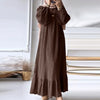 Une femme portant une longue robe bohème marron à volants et un hijab beige clair.