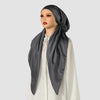 A woman wearing an elegant satin silk instant hijab scarf in dark gray and white attire.