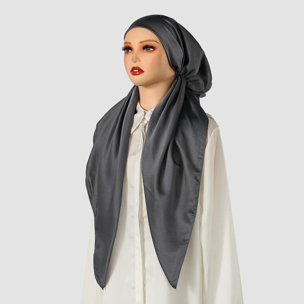 Eine Frau trägt einen dunkelgrauen satinigen Seidenschal als Instant-Hijab über einem weißen Oberteil.