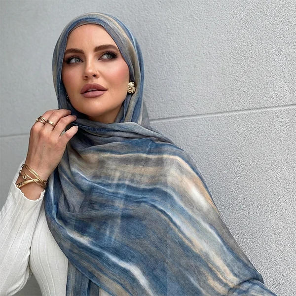 A woman wearing a blue and gray watercolor patterned hijab scarf