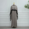 Vestido abaya largo color topo con ribetes de encaje negro y un broche dorado, exhibido en maniquí.