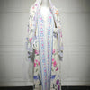 Vestido kaftan blanco maxi con estampado floral de flores rosa, azul y morado exhibido en maniquí.