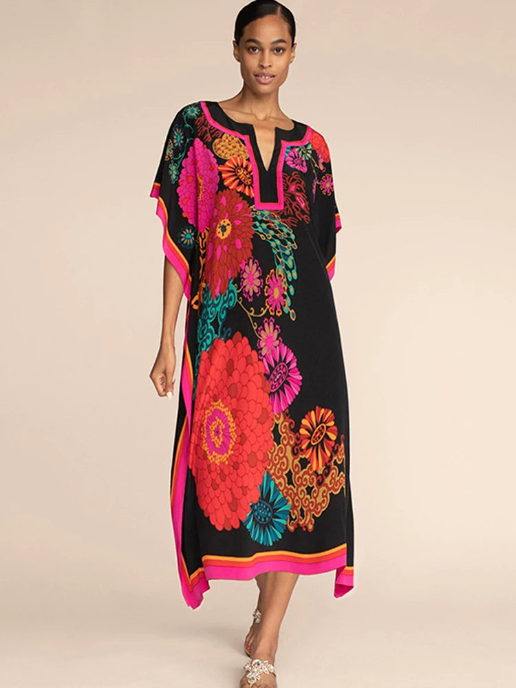 Una modelo lleva un vestido kaftan negro con estampados florales vibrantes en rosa, naranja y turquesa.