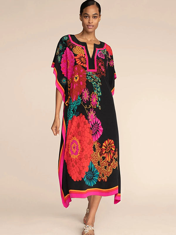 A model wears a black kaftan dress featuring vibrant floral prints in pink, orange, and teal.