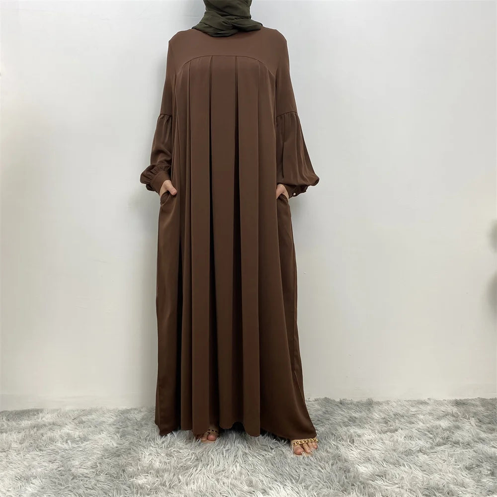 Langes, fließendes braunes islamisches Kleid für Frauen, präsentiert vor weißem Hintergrund.