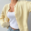 Une femme portant un pull tricoté jaune sur un haut blanc et un jean bleu.