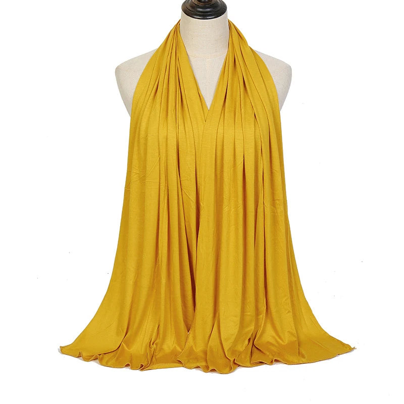 A mustard yellow soft modal jersey hijab scarf draped around a mannequin's neck.