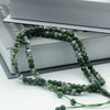 Green beads of a 99 bead Islamic prayer tasbih laid across a stack of books.