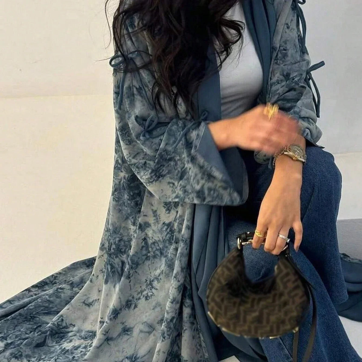 Eine Frau trägt ein fließendes Tie-Dye Abaya Kaftan in blau-grauem Stoff und einem hellgrauen Oberteil.