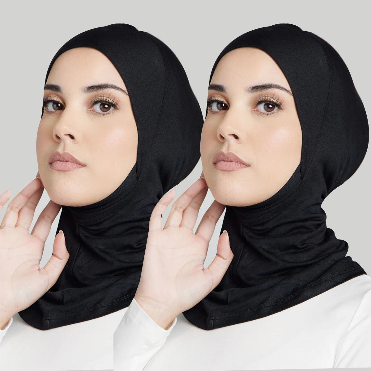 Eine Frau trägt eine schwarze weiche Modal-Turban-Hijab-Kappe und blickt direkt in die Kamera.