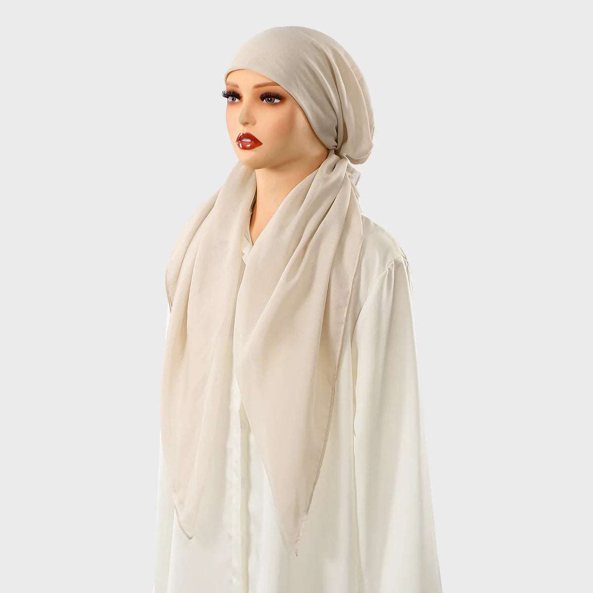 Une femme portant un hijab carré beige uni et une tenue assortie fluide.