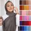 Eine Frau modelliert einen einfarbigen braunen Chiffon-Hijabschal mit weißer Kleidung.