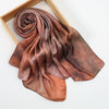 Un foulard hijab en satin de soie brun terreux drapé est exposé dans un cadre en bois.