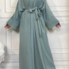 A long, flowing sage green abaya and kaftan set worn by a model.