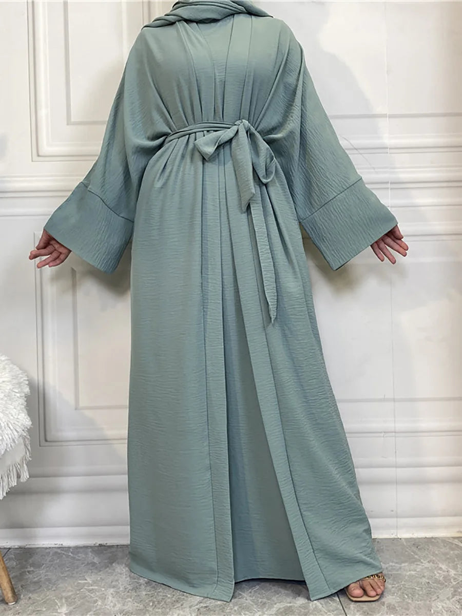 A long, flowing sage green abaya and kaftan set worn by a model.