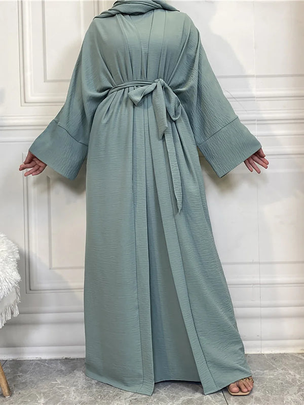 A long, flowing sage green abaya and kaftan set worn by a model.