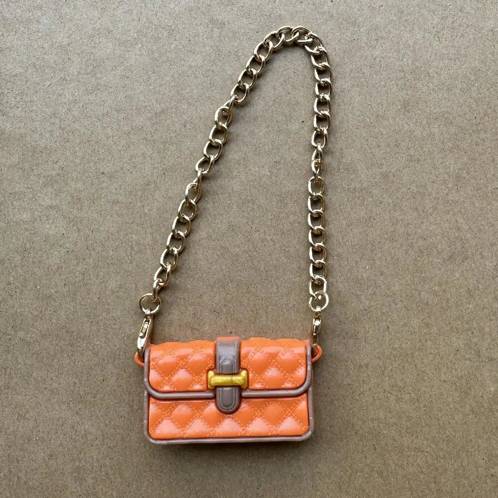 Bolso de cuero acolchado naranja con correa de cadena dorada mostrado sobre fondo gris neutro.