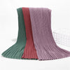 Ein Stapel von Crinkle-Chiffon-Hijab-Schals in Grüntönen, Pink und Mauve.