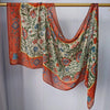 Mehrfarbiger Hijab-Schal mit Blumenmuster in Orange, Grün und Blau, aufgehängt.