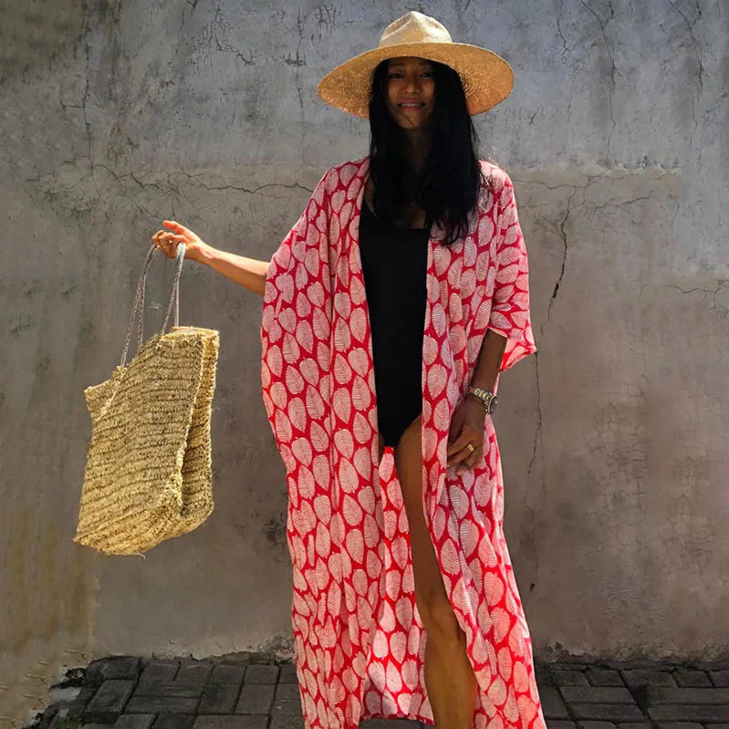 Eine Frau in einem rot-weißen gemusterten Kimono-Überkleid steht vor einer strukturierten Wand.