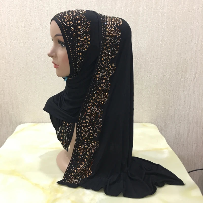 Une femme portant un élégant hijab noir avec des ornements en cristal doré.