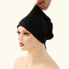 A black adjustable elastic headband hijab cap being placed on a female mannequin's head.