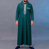 A man wearing a dark teal Moroccan embroidered thobe jellaba with silver trim.