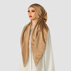 A woman models an elegant satin silk instant hijab scarf in a beige color draped around her head and neck.