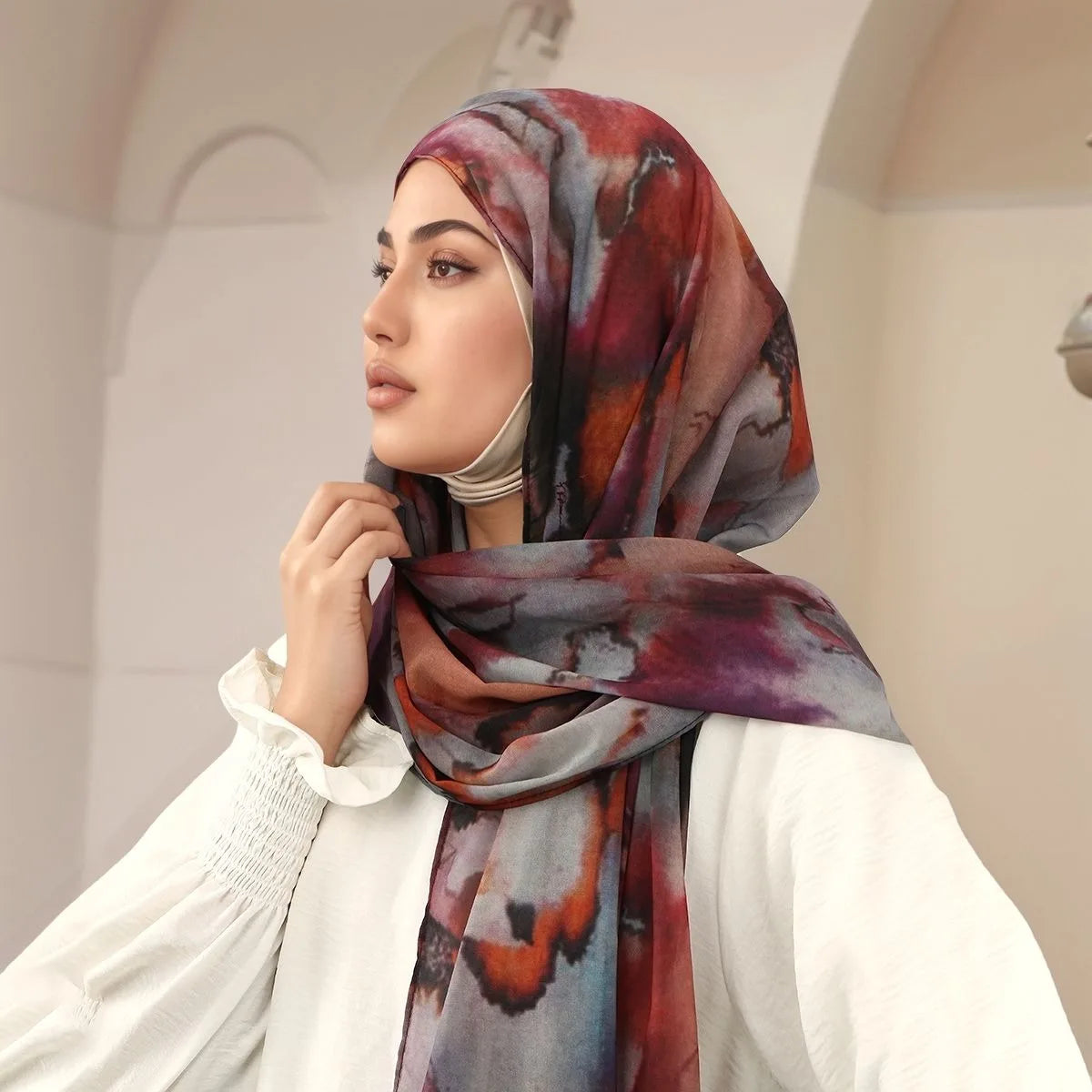 Eine Frau trägt einen Aquarell-Chiffon-Instant-Hijab in tiefen Rot-, Violett- und Grautönen.