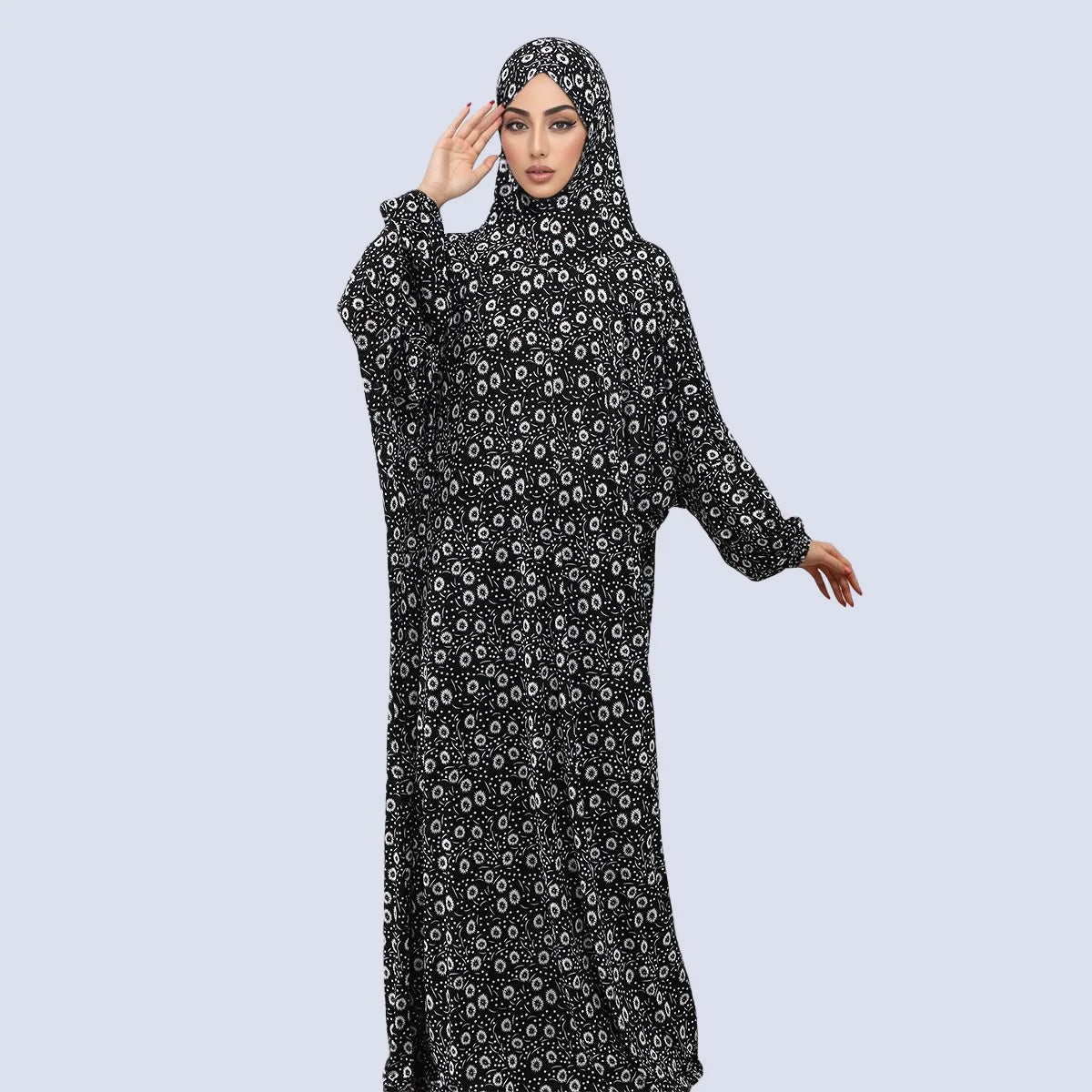 A woman wearing an elegant black and white patterned Muslim hijab dress for prayer and daily wear.