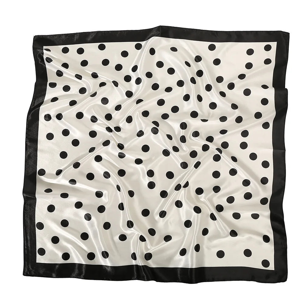 Elegant silk scarf with a white background and black polka dots, displayed flat.