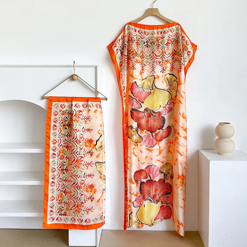 Orange Kaftan-Kleid mit Blumenmuster in Pink und Gelb, auf einem Hanger.