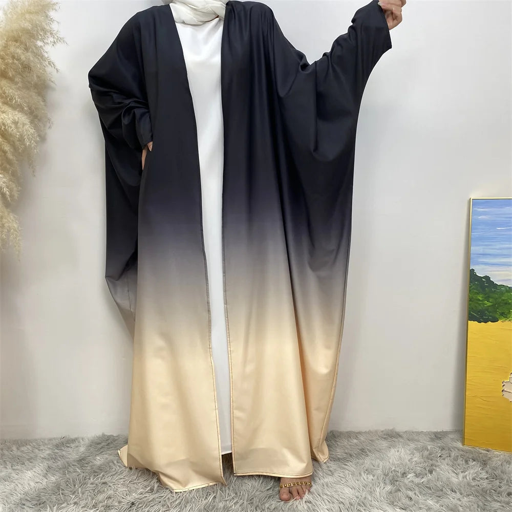 Pijama o bata fluida negra y beige elegante, usada por una persona contra una pared blanca.