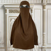 Braune elegante Maxi-Abaya auf einem Mannequin vor weißer verzierten Wandvertäfelungen.