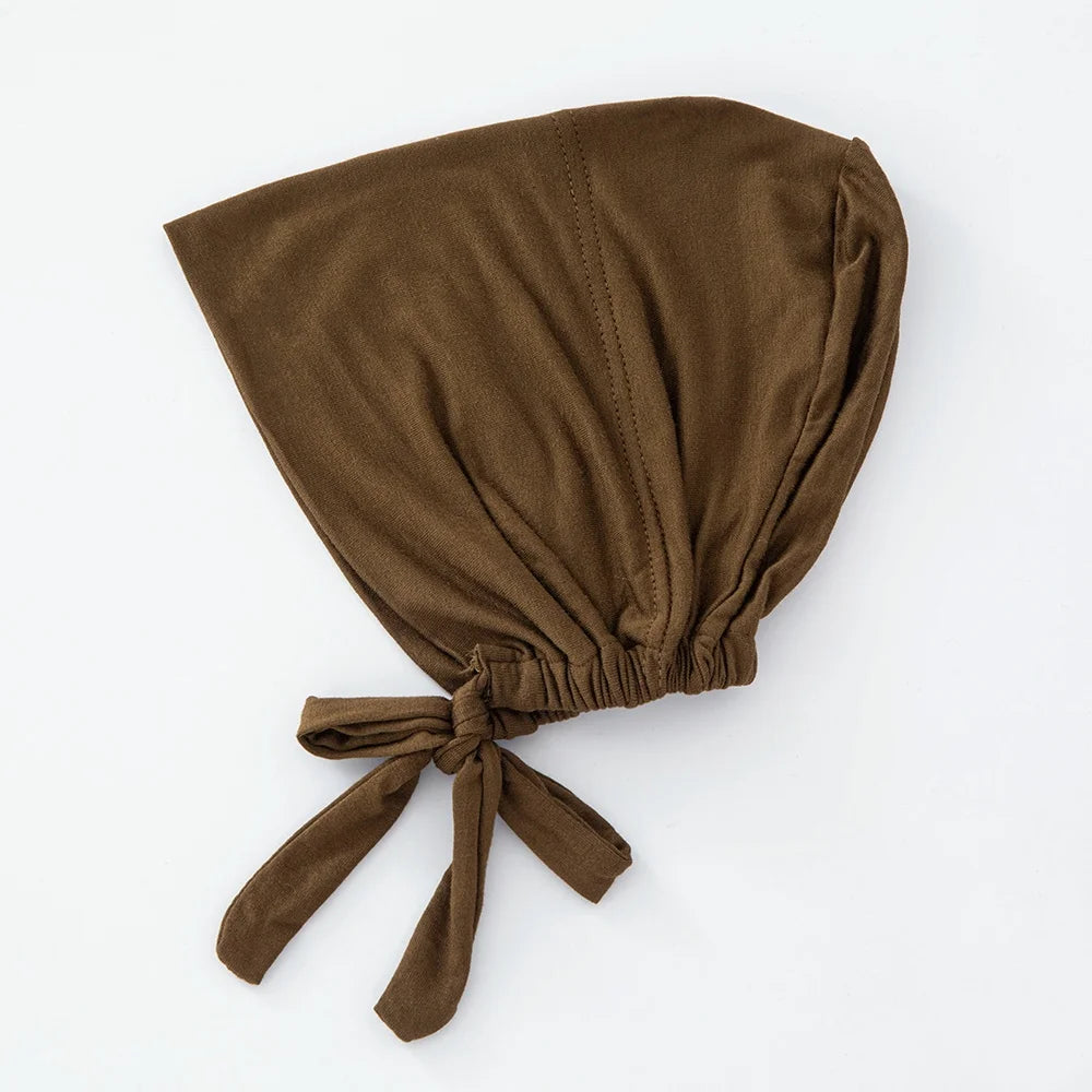 Ein einfarbiger brauner, mehrfarbiger Turban-Inner-Hijab-Bonnet, gefaltet und auf weißem Hintergrund präsentiert.