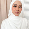 A woman wearing a white hijab and matching inner scarf set looking at the camera.