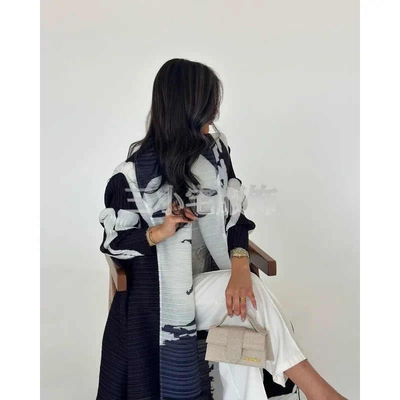 Une femme modélise une veste coupe-vent plissée à imprimé rétro noir et blanc avec un pantalon blanc.