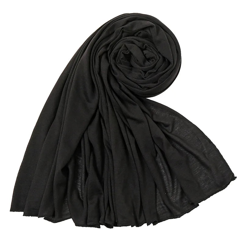 Un foulard hijab en jersey de coton noir et élégant, roulé et drapé, montrant sa texture douce.