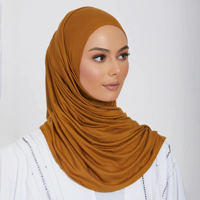A woman wearing a solid mustard brown stretchy jersey plain hijab scarf and white clothing.