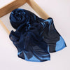 Un foulard voile imprimé bleu foncé et bleu drapé sur un cadre en bois.