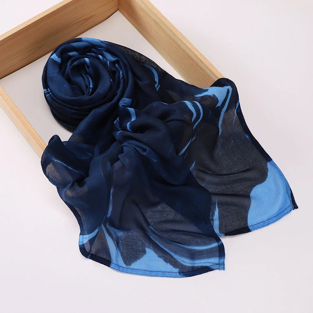 Un foulard voile imprimé bleu foncé et bleu drapé sur un cadre en bois.