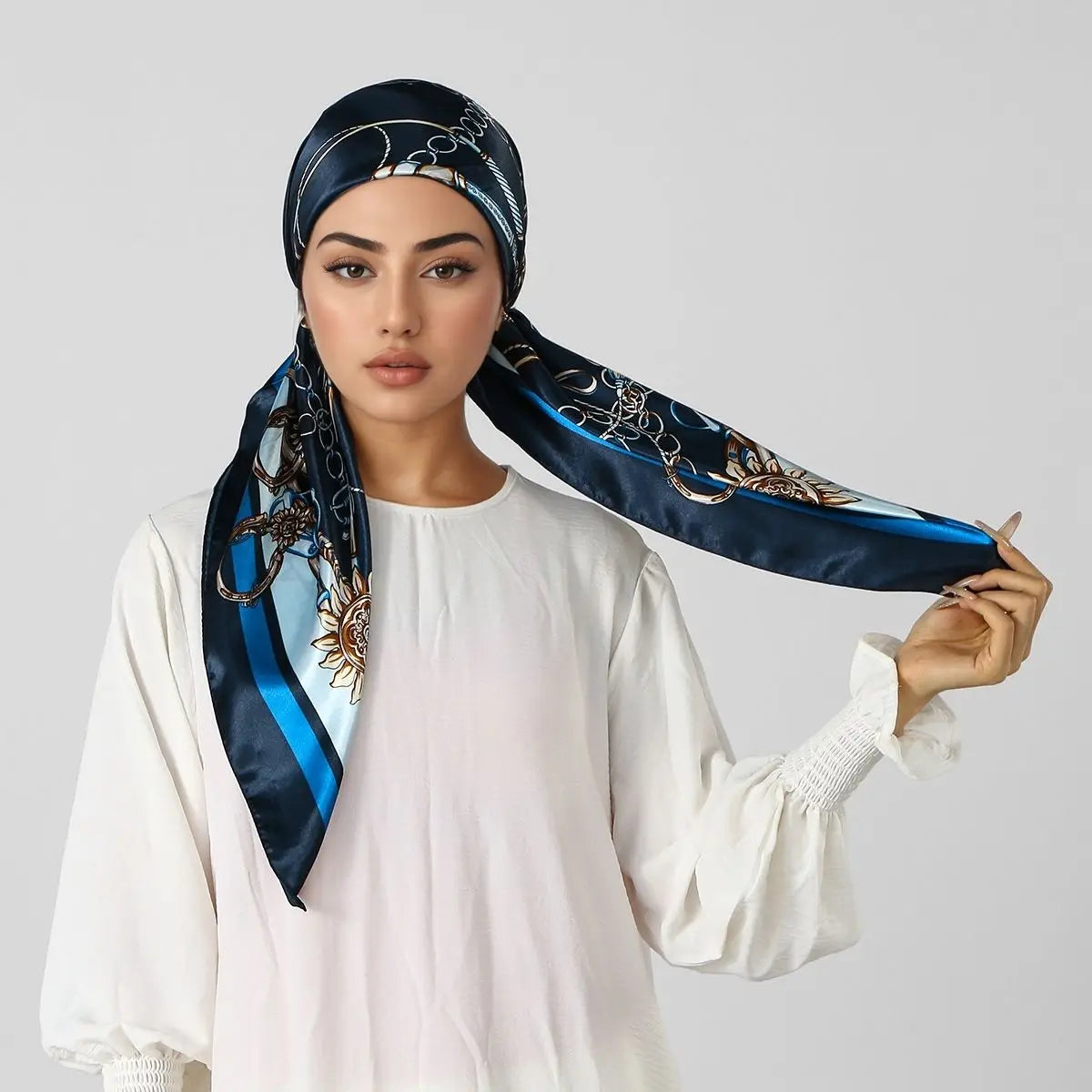 A woman models an elegant satin silk instant hijab scarf in navy blue with gold embroidery.