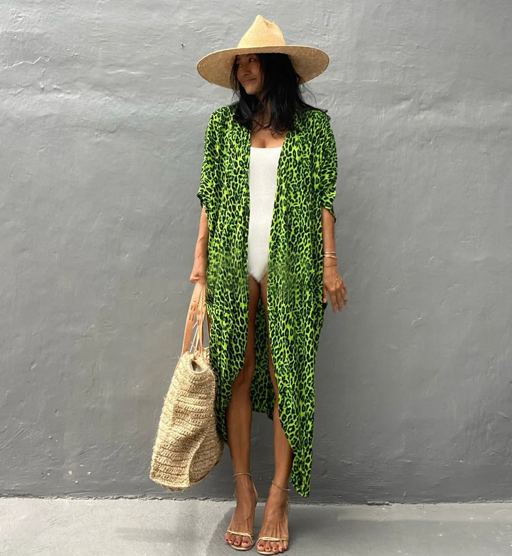 Eine Frau in einem weißen Kleid und einem grünen Leopardenmuster-Kimono-Überwurf mit Strohhut und geflochtenem Beutel.