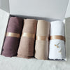 Eine Box mit vier zerknitterten Schals oder Hijabs in Mauve-, Beige- und Weißtönen.