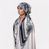 A woman wearing an elegant satin silk instant hijab scarf with blue and white floral patterns.