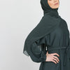 Eine Frau trägt eine dunkeltürkise marokkanische Kaftan-Abaya mit einem drapierten Kopftuch.