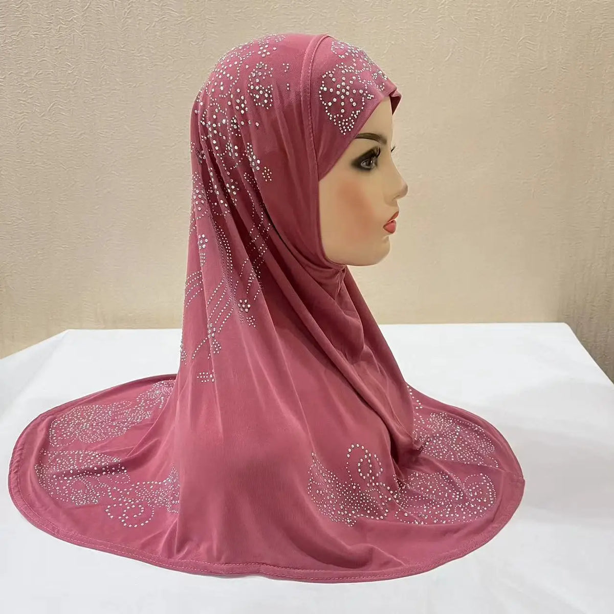Nahaufnahme eines staubrosa muslimischen Hijab-Schals, verziert mit funkelnden Strasssteinen.