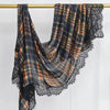 A plaid modal hijab scarf featuring earthy tones and black lace trim, hanging on a wooden rod.