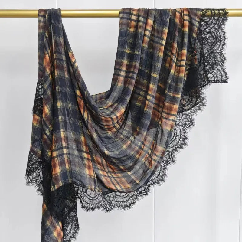 A plaid modal hijab scarf featuring earthy tones and black lace trim, hanging on a wooden rod.